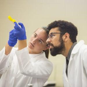 Student and professor examining test tube.